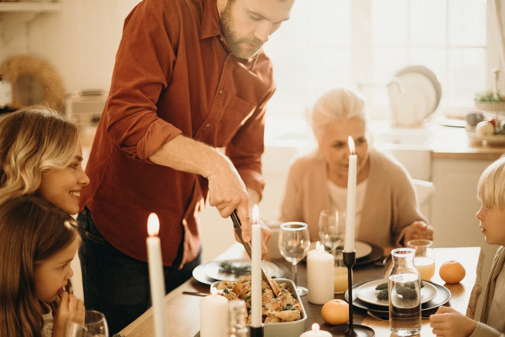 A warm family gathering around a festive Thanksgiving dinner table with candles and smiles.
