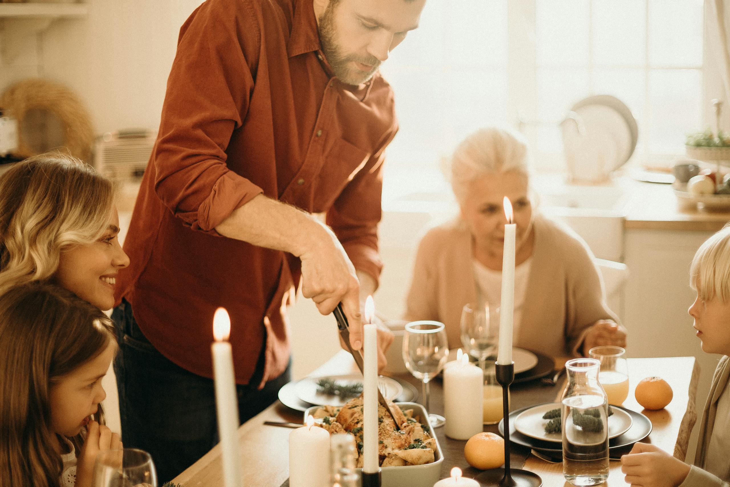 A warm family gathering around a festive Thanksgiving dinner table with candles and smiles.