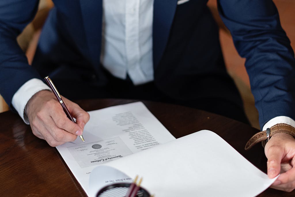 A professional individual signs estate planning legal documents at a desk in an office setting.