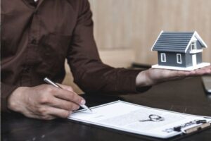 MAN HOLIDNG THE HOUSE AND SIGNING THE PAPER