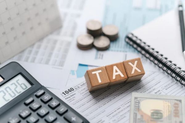 tax in scrabble with calculator and a tax paper with money